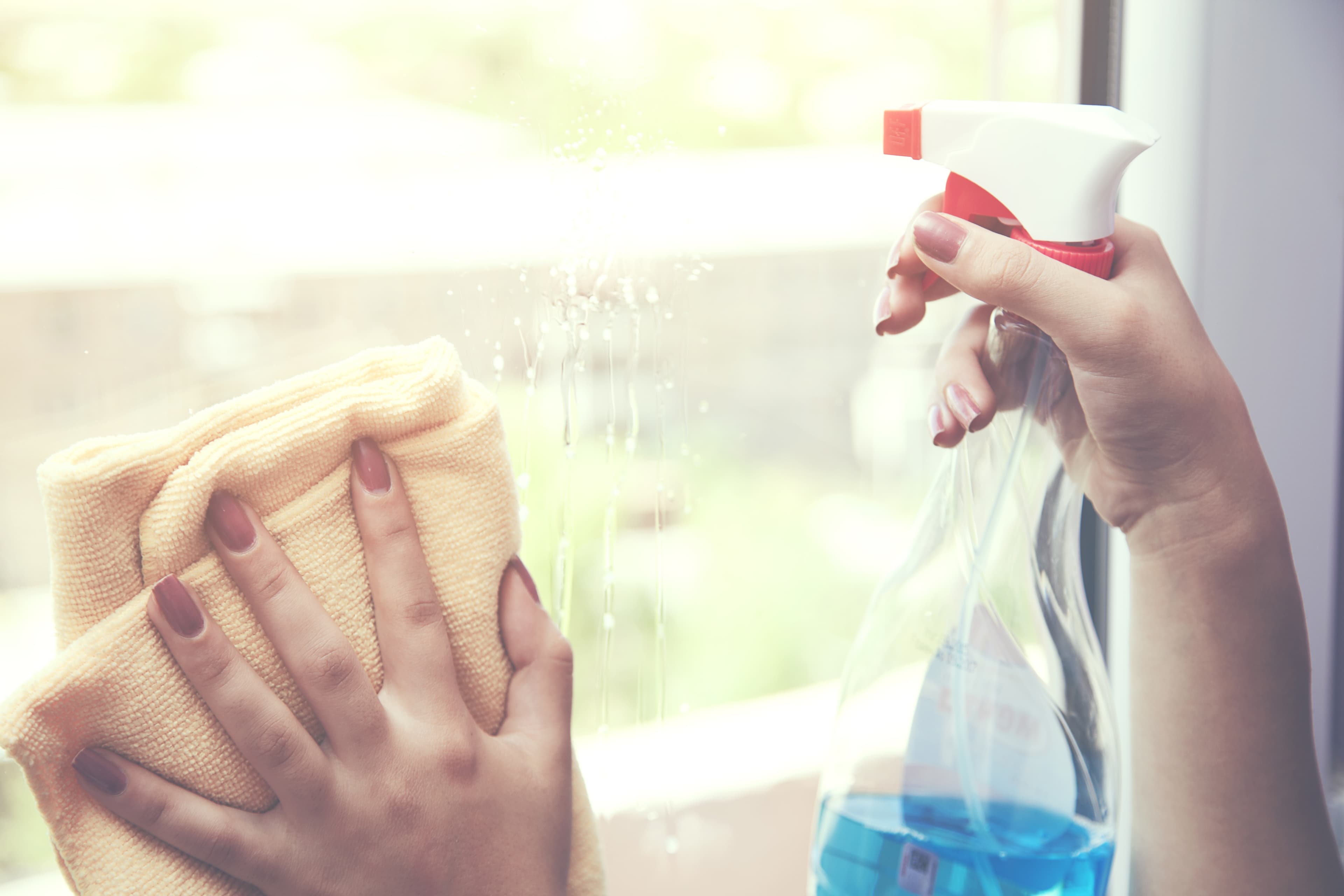 Gloved Hands Spray-Cleaning a Metal Surface